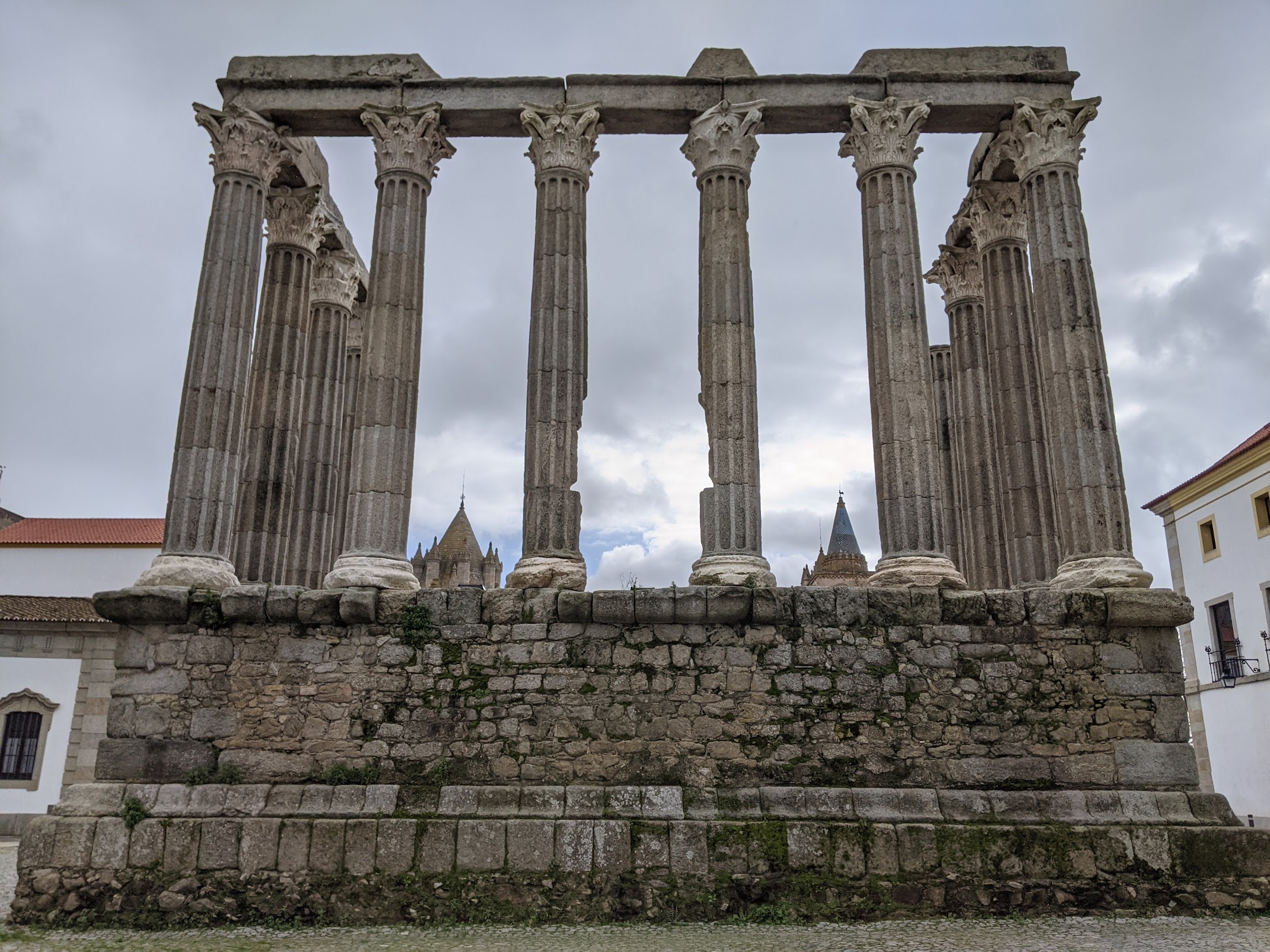 Templo Romano de Évora visto de frente, com as colunas coríntias e as torres da Catedral ao fundo