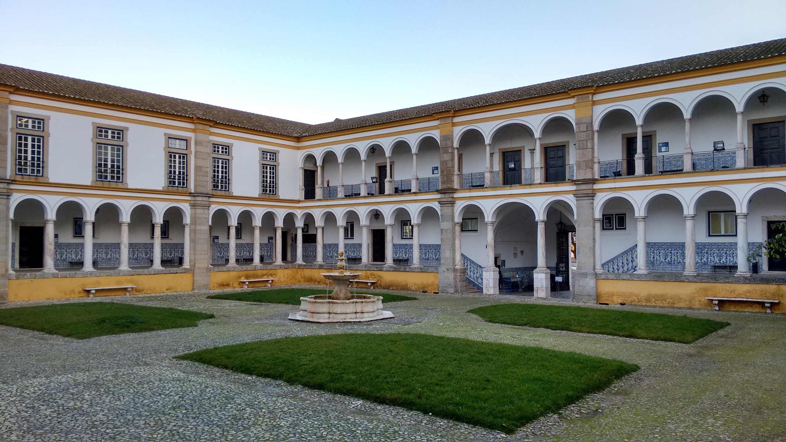 Claustro da Universidade de Évora com arcadas, azulejos e fonte central